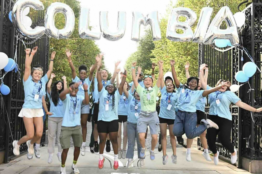 Orientation volunteers show their excitement for the Class of 2028 at the main Broadway gate.